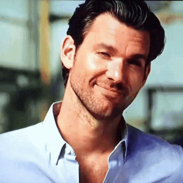 a man with a beard wearing a blue shirt smiles