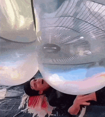 a man is laying in a balloon with a fan blowing on him .