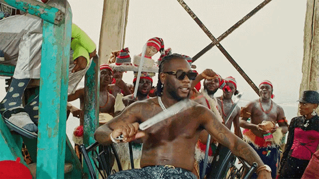 a man without a shirt is holding a knife in front of a crowd of people