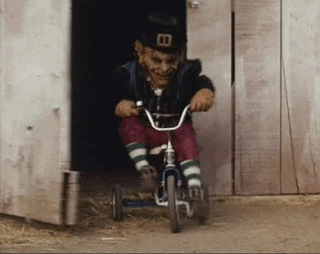a leprechaun is riding a tricycle in front of a wooden building