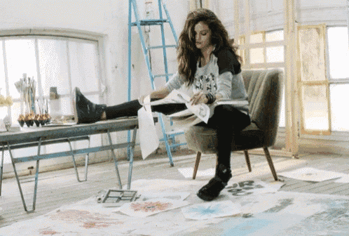 a woman is sitting in a chair with her legs crossed and a book in her hand