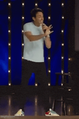 a man is standing on a stage with a microphone and the words technically speaking behind him