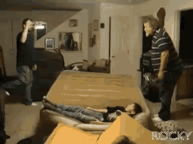 a man taking a picture of a boy laying on a couch with the word rocky on the bottom right