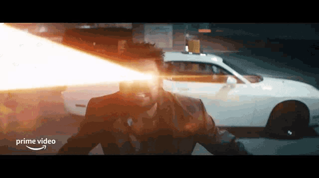 a man is standing in front of a white car and a light is coming out of his eyes .