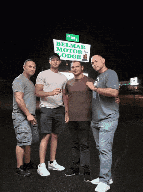 four men standing in front of a sign that says belmar motor lodge
