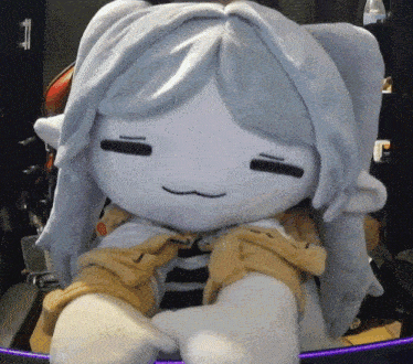 a stuffed animal with long white hair is sitting on a desk