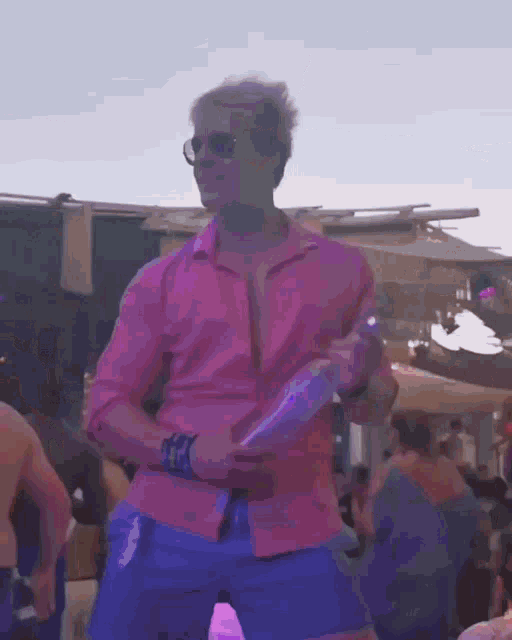 a man in a pink shirt and blue shorts is dancing in a crowd