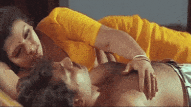 a woman in a yellow shirt is laying on top of a man 's chest