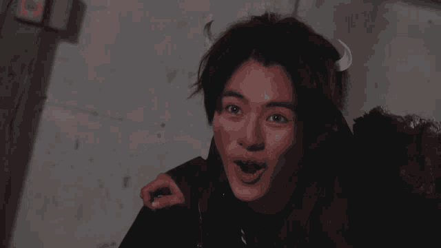 a young asian man with horns on his head is smiling