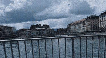 a fence surrounds a body of water with buildings in the background including one that says ' l' ermitage '