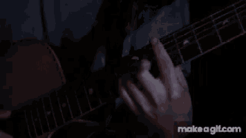 a person is playing an acoustic guitar in a dark room with make a gif.com in the corner