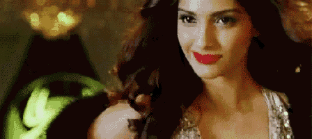 a close up of a woman wearing red lipstick and a sequined top .