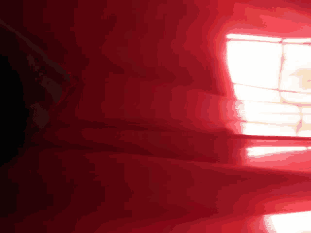 a window with a red curtain and a light shining through it