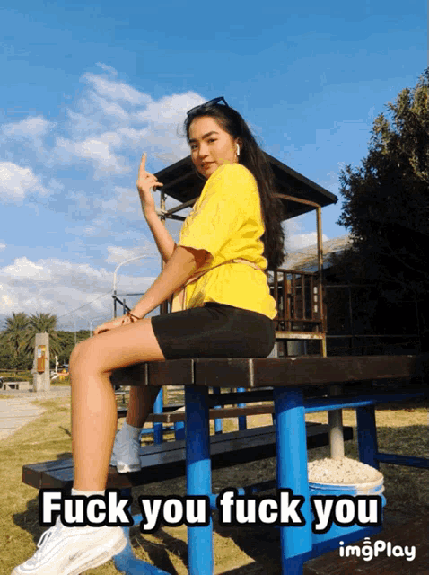 a girl sitting on a picnic table with the words " fuck you fuck you " written below her