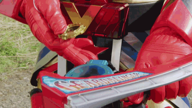 a person in a red glove is holding a toy sword that says samurai 2