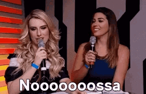 two women are sitting next to each other holding microphones and one of them is saying noooooossa