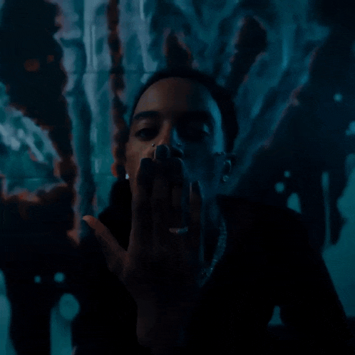 a man with a nose ring is giving the middle finger in front of a painting