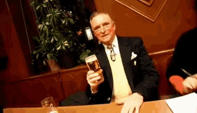 a man in a suit and tie holds a glass of beer