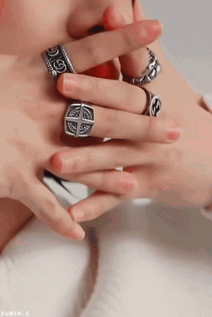 a person is wearing a lot of rings on their fingers .