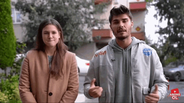 a man and a woman are standing next to each other with the man wearing a nasa jacket