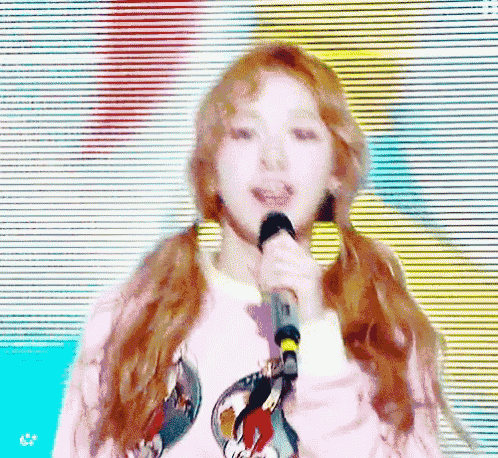 a woman with pigtails is singing into a microphone on a stage .
