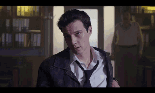 a man wearing a tie and a leather jacket looks at the camera