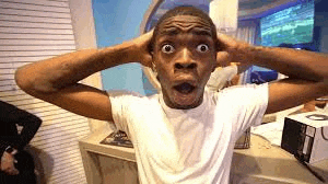 a man in a white shirt is making a surprised face while holding his head .