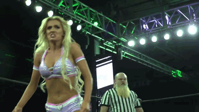 a blonde woman in a wrestling ring with a referee in the background
