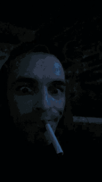 a man smoking a cigarette in the dark