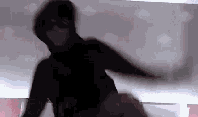 a silhouette of a person in a black hoodie is dancing .