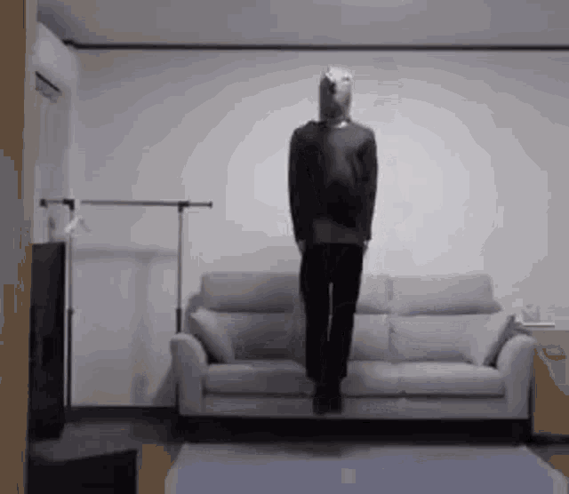 a person is jumping in the air in front of a couch .