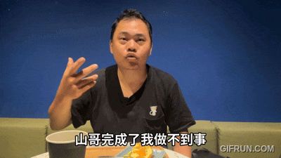 a man in a black shirt is sitting at a table with a plate of food and a gifrun.com watermark