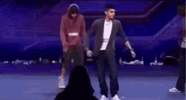 a group of men are dancing on a stage with a woman watching .