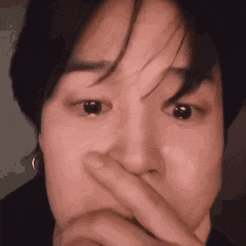 a close up of a person covering their face with their hand .