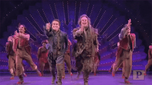 a group of men are dancing on a stage in front of a crowd .