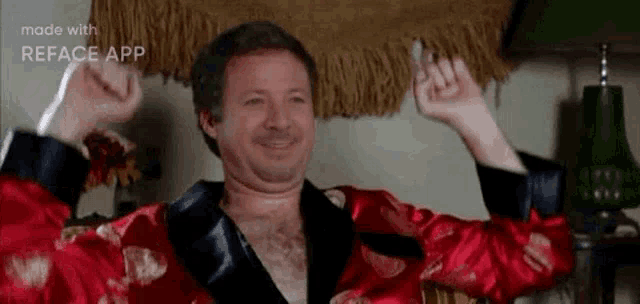 a man is wearing a red robe and smoking a cigarette while raising his arms in the air .