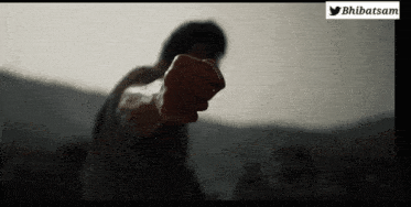a man 's fist is pointing at the camera with a twitter logo in the background