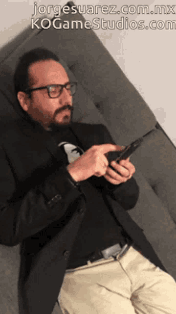a man sitting on a couch looking at his phone with the website jorge suarez.com.mx written above him
