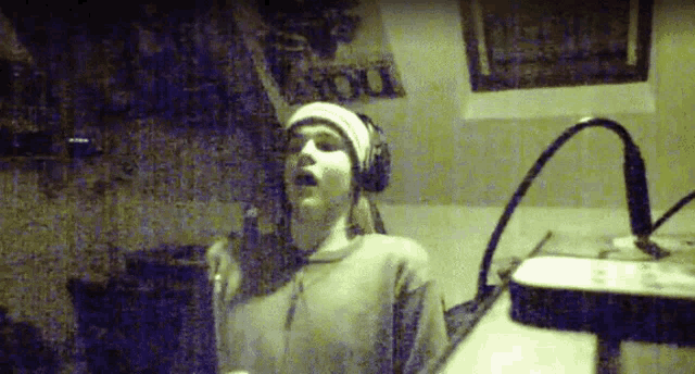 a person wearing headphones is singing into a microphone in front of a sign that says " you "