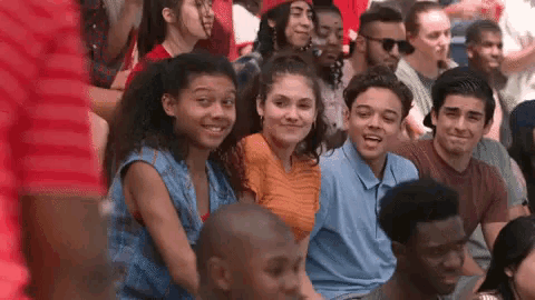 a group of young people are sitting in a stadium watching a game and smiling .