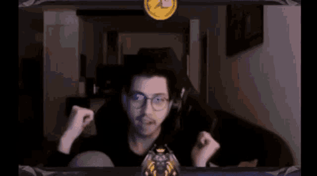 a man wearing glasses and headphones is sitting in front of a screen with a gold coin on it