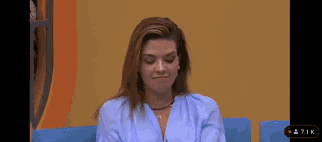 a woman is sitting on a blue couch in front of a yellow wall .