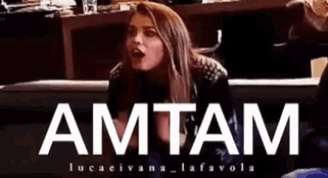 a woman is sitting in front of a sign that says amtam .