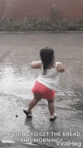 a little girl is dancing in the rain in the street .