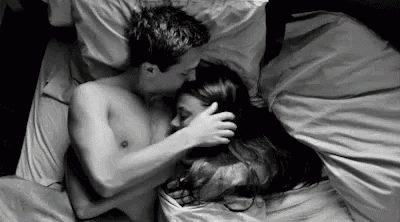a man and a woman are hugging each other in bed .