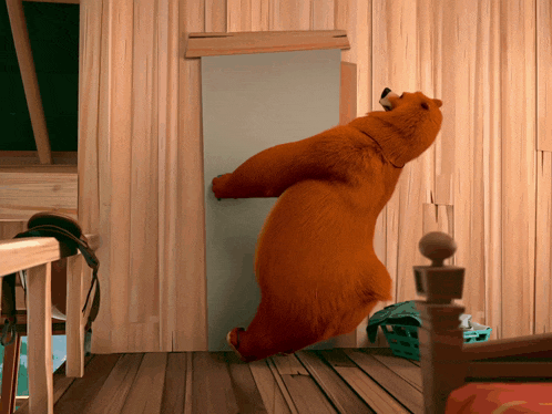 a brown bear is standing on its hind legs in a room