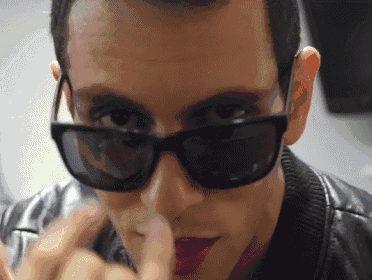 a man wearing sunglasses holds his finger to his lips