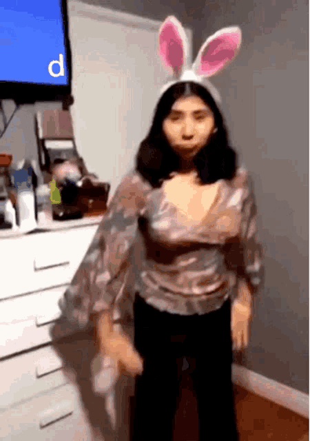 a woman wearing bunny ears is dancing in front of a tv with the letter p on it