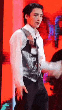 a man in a vest and tie is standing on a stage .