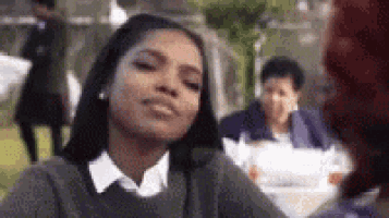 a woman is making a funny face while sitting at a table with a group of people .